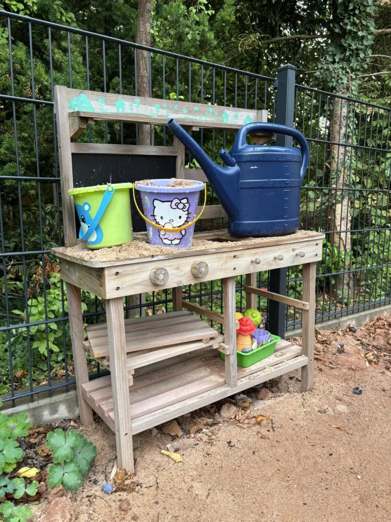 Matschküche am Gartenzaun hinter dem Spielhaus zum kreativen Spielen mit Erde und Wasser