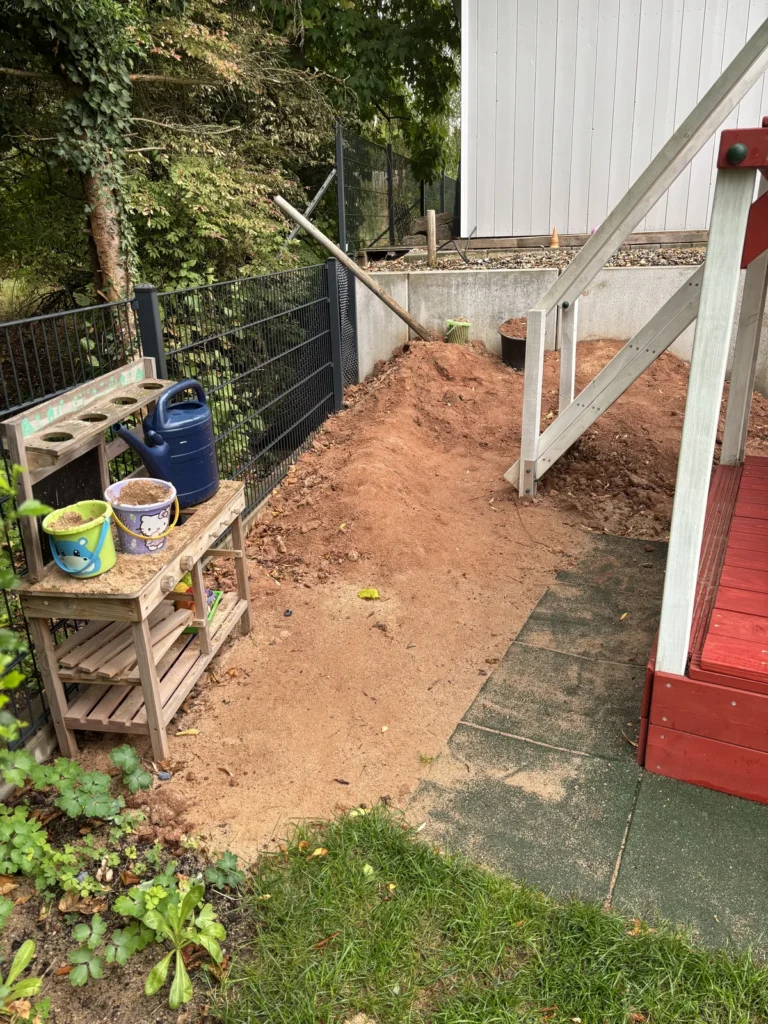 Matschküche und Matschberg hinter dem Spielturm mit etwa drei Metern Abstand