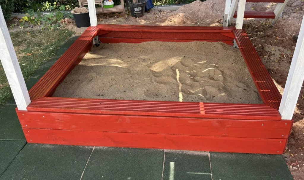 Erweiterter Wickey Smart Seaway Sandkasten im Garten mit umlaufender Sitzbank