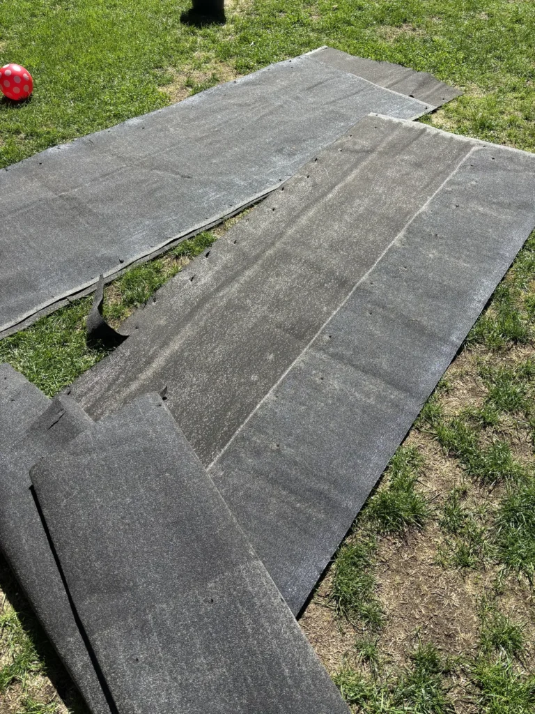 Entfernte alte Dachpappe des Gartenhauses auf dem Rasen