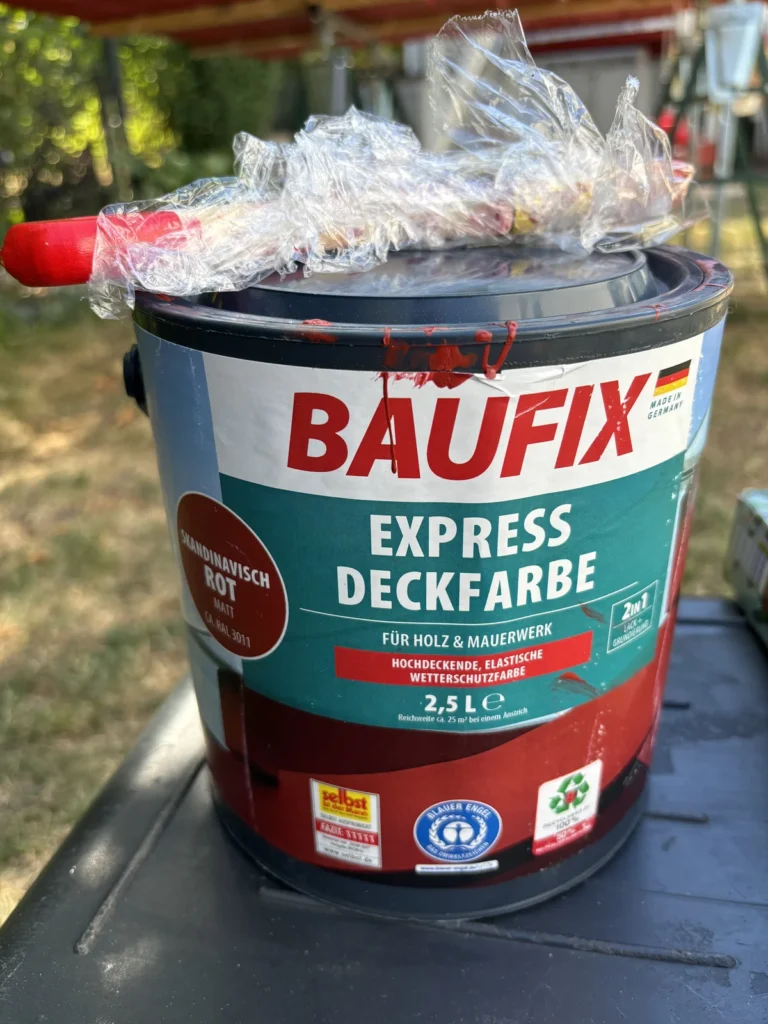 BAUFIX Express Deckfarbe in Skandinavisch Rot mit eingewickeltem Pinsel beim Spielturm streichen