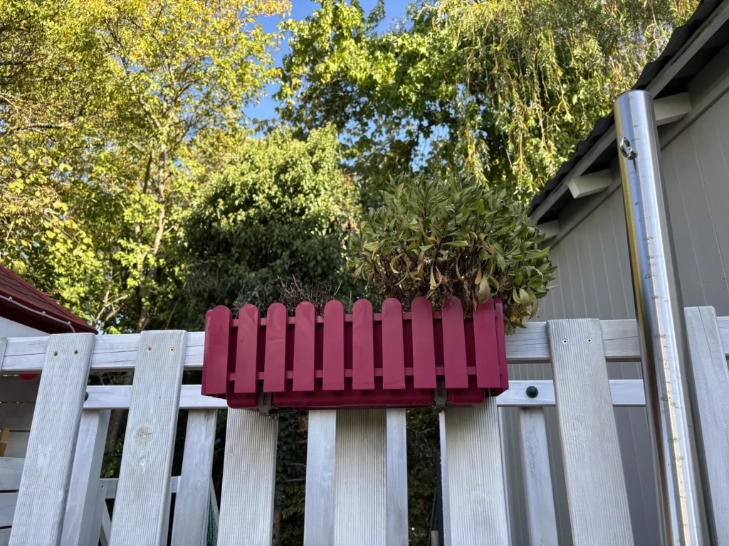 Blumenkasten an einer Holzbrücke zwischen zwei Gärten