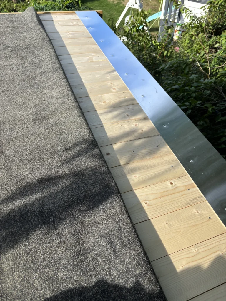 Montage des Traufblechs am Gartenhausdach mit zurückgeklappter Dachpappe