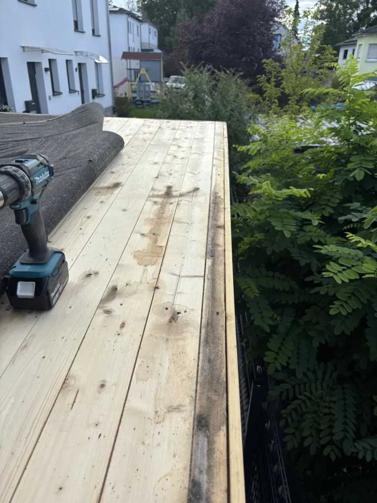 Wasserverfärbungen am Holz unter der alten Dachpappe des Gartenhauses