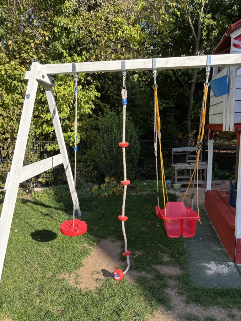 Knotenseil und Tellerschaukel am Schaukelbalken eines Spielturms