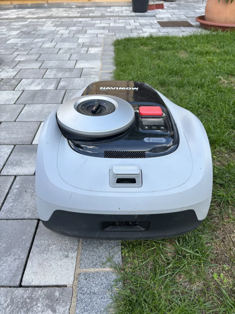 Navimow i105e fährt entlang der befahrbaren Mähkante am Weg zum Gartenhaus