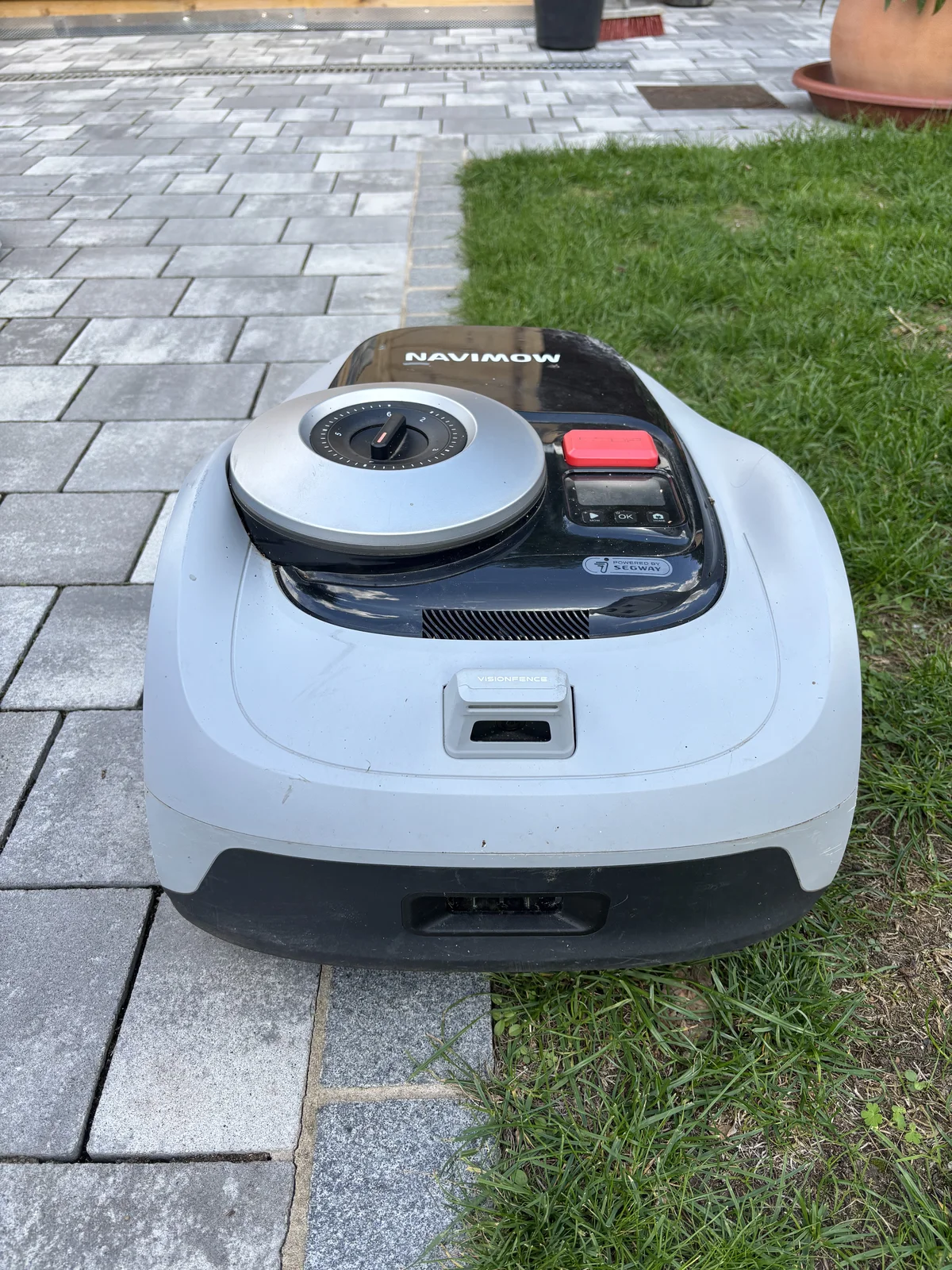 Navimow i105e fährt entlang der befahrbaren Mähkante am Weg zum Gartenhaus