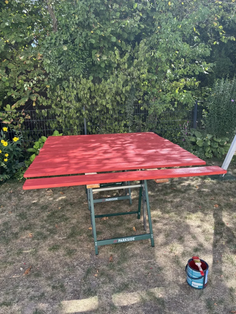 Rot gestrichene Douglasienbretter des Sandkasten Klappdeckels beim Trocknen