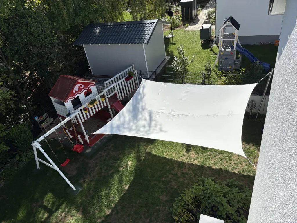 Fertig befestigtes Sonnensegel mit drei Masten und vier Befestigungspunkten aus der Vogelperspektive