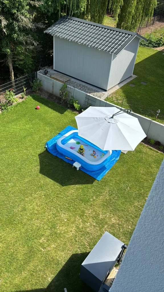 Sonnenschirm mit aufblasbarem Pool auf der Rasenfläche vor der Anschaffung des Sonnensegels