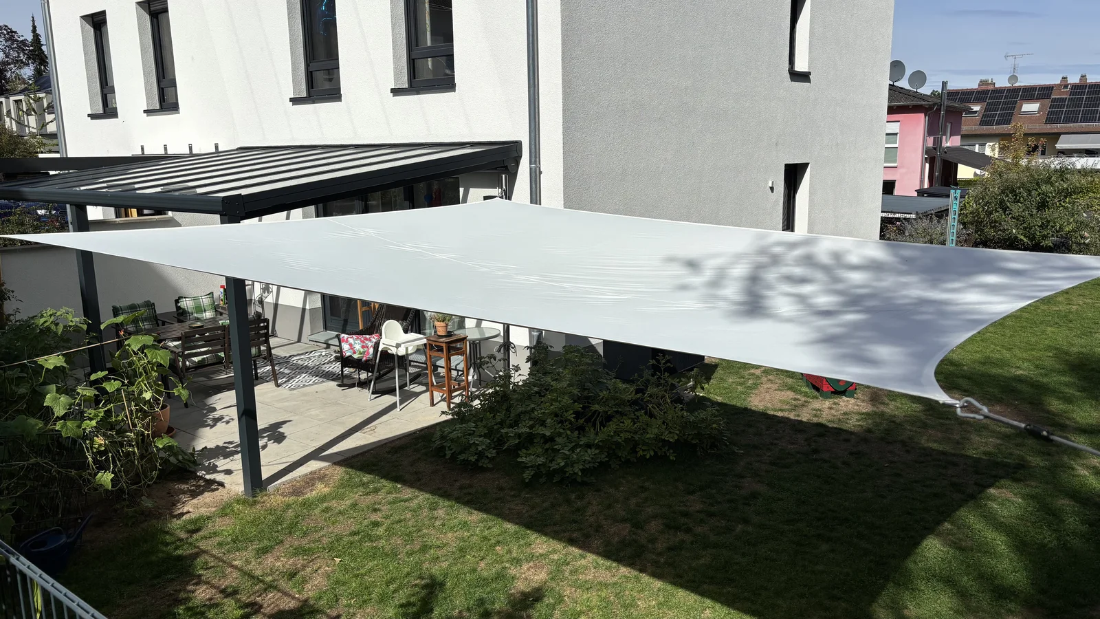 Sonnensegel im Garten zwischen Spielturm und Terrasse mit beschatteter Rasenfläche