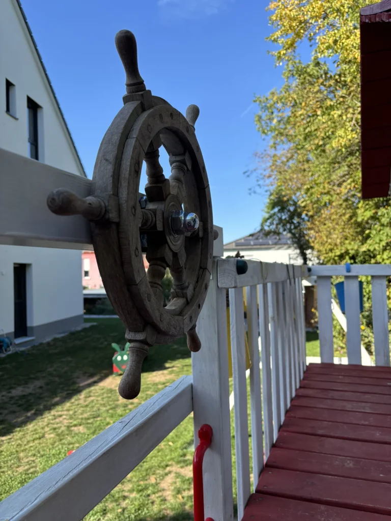 Holzsteuerrad auf einem Kantholz über der Rutsche des Spielturms
