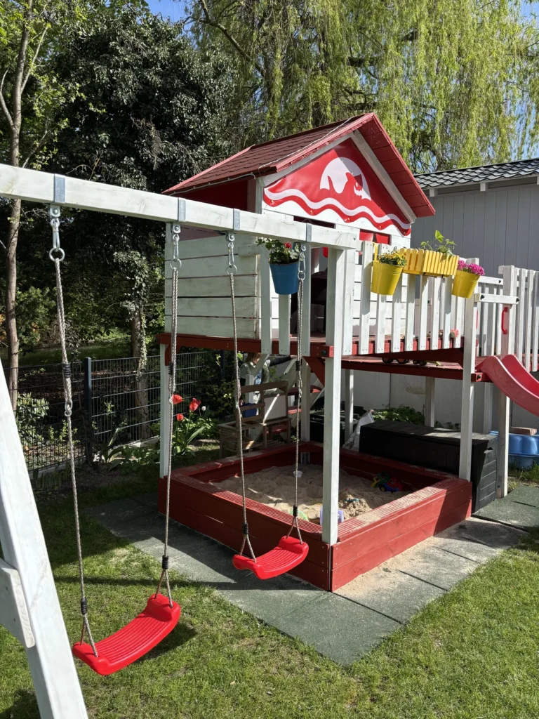 Fertig aufgebauter Spielturm mit Schaukel und Fallschutzmatten