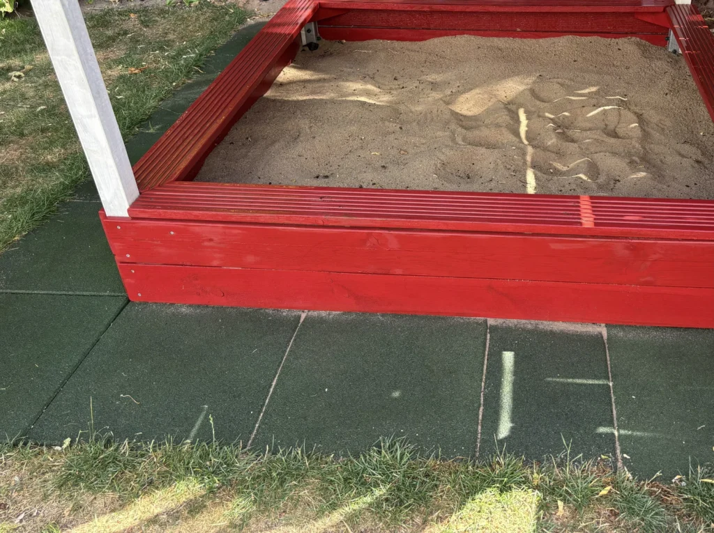 Selbst gebauter Sandkasten mit Sitzfläche unter dem Spielturm
