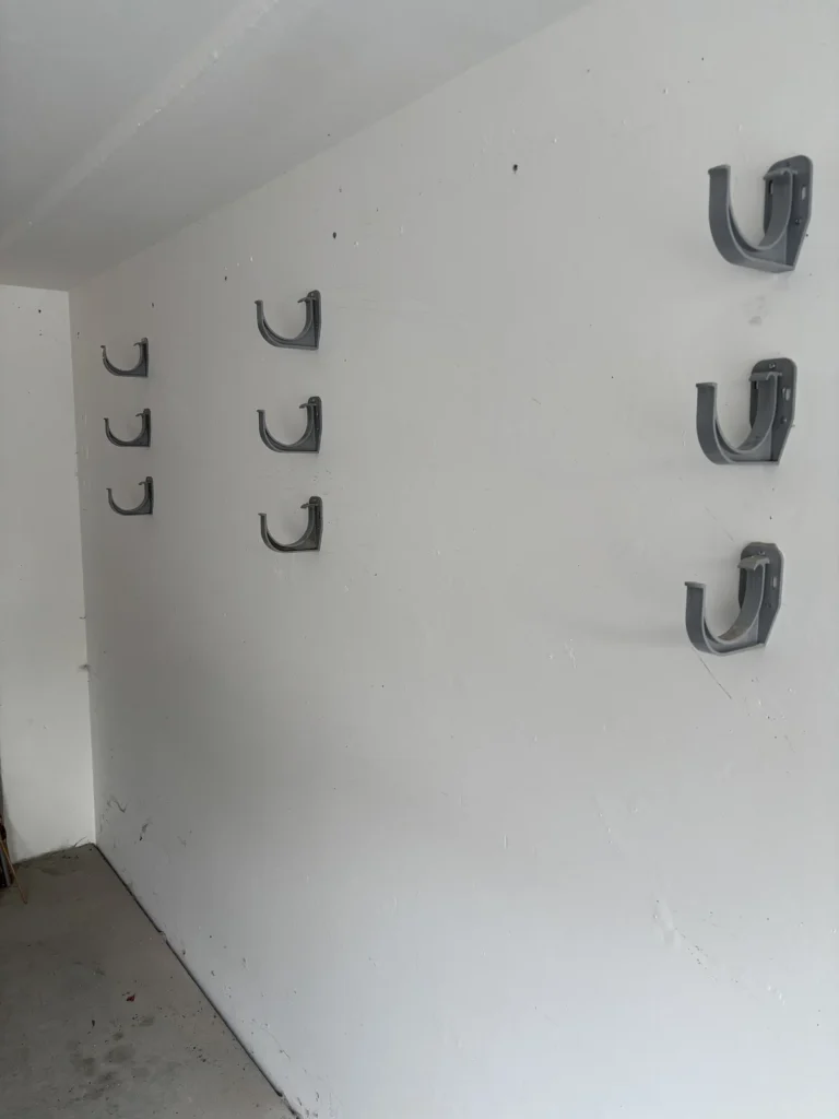 Neun Dachrinnenhalter an der Betonwand der Garage für drei Sonnensegelmasten